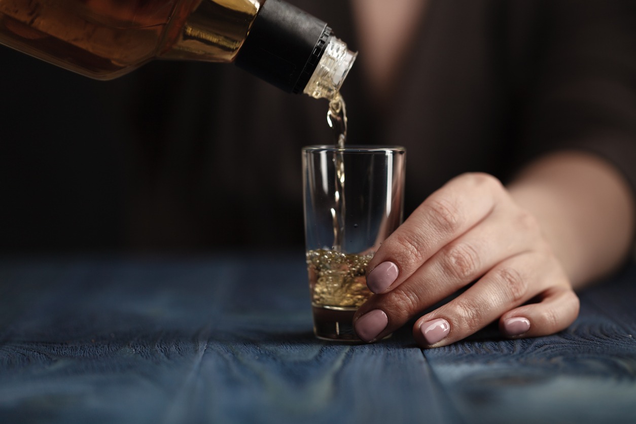 Alcohol Abuse - Female pouring whiskey in to glass shot