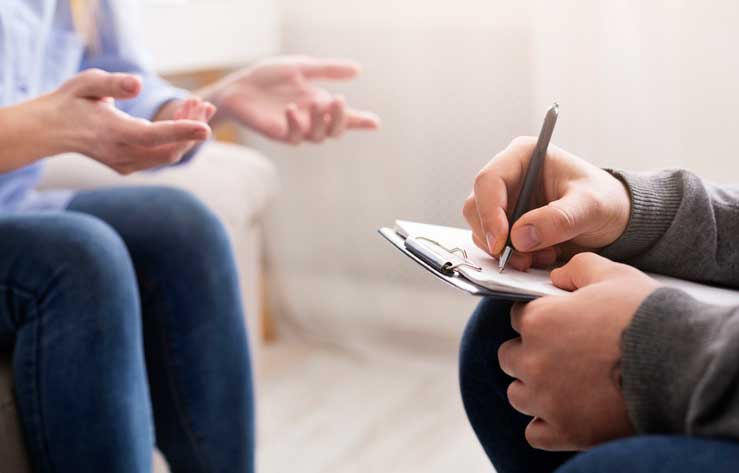 Two people talking and one writing notes