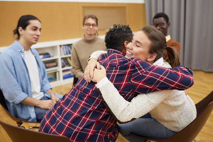 Two people in a group hugging