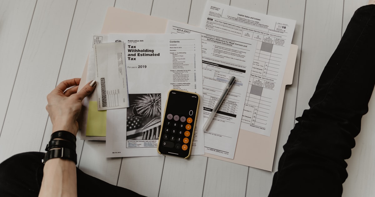 Hand with calculator and pen on paperwork, representing planning the financial cost of rehab in San Diego