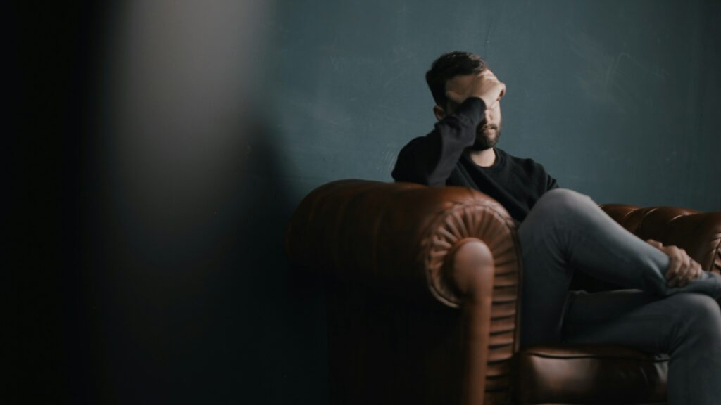 Man sitting alone in a chair with his head down struggling with anger and addiction