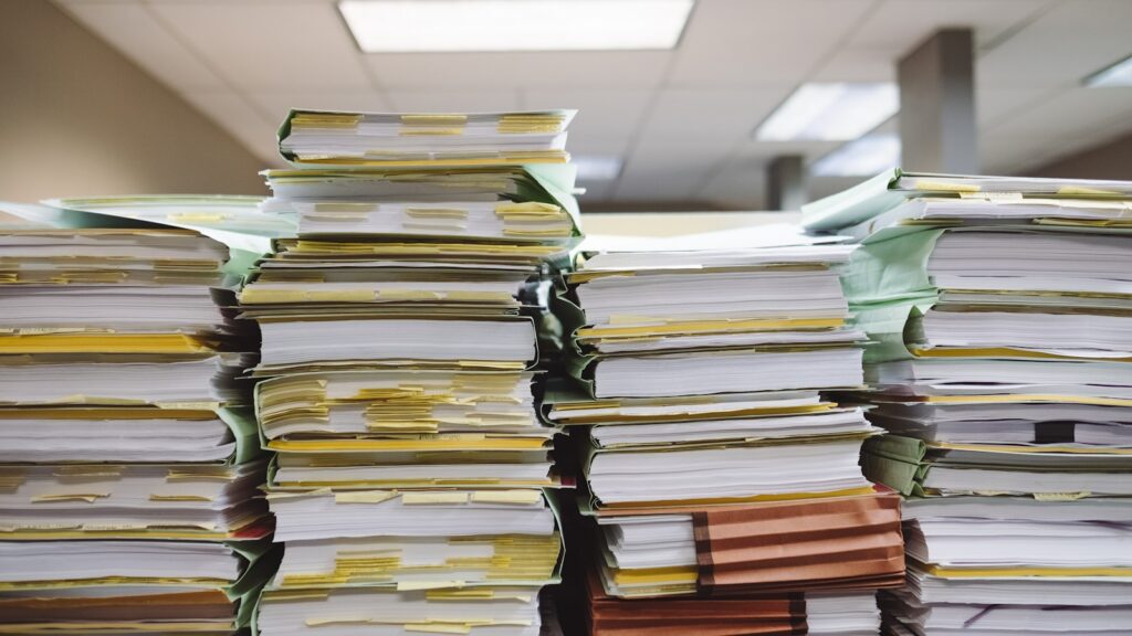 Stacks of paper files and folders representing rehab insurance claims paperwork
