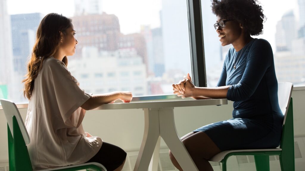 Two women talking across a table during a hopeful counseling conversation