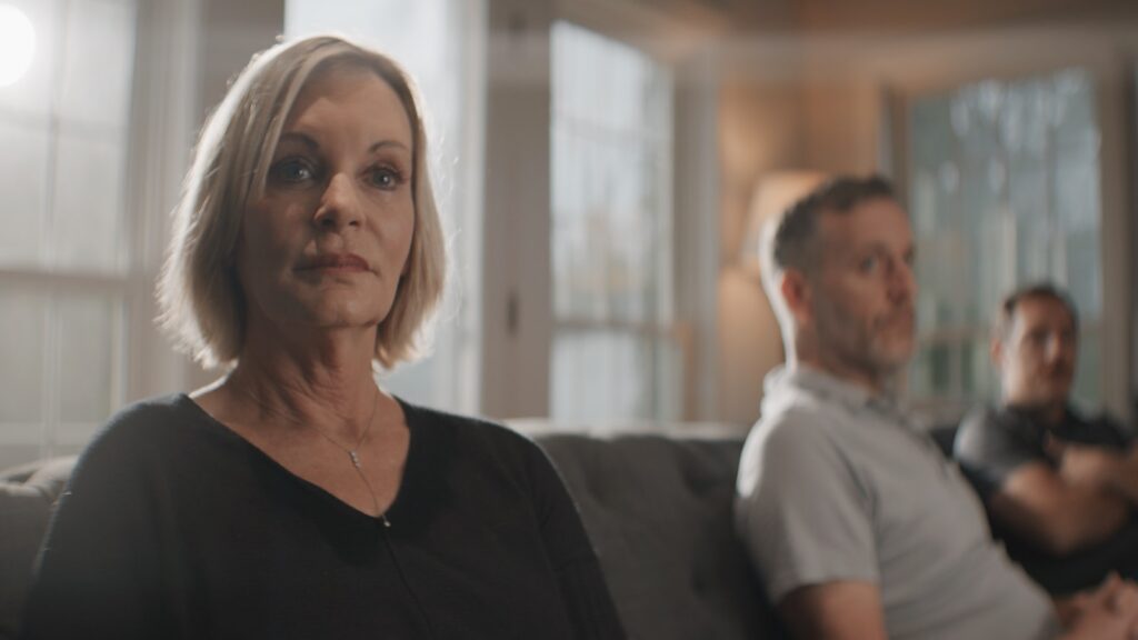 Woman looking away thoughtfully while a family group talks behind her