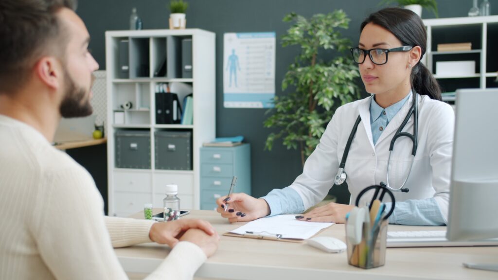 Doctor consulting with a young male patient in a clinic exam room