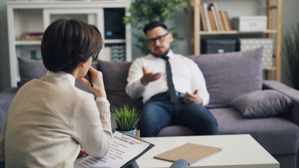 Parent and a man talking seriously while seated in a living room