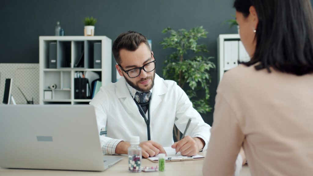 Physician writing notes while consulting a patient about alcohol-related health risks