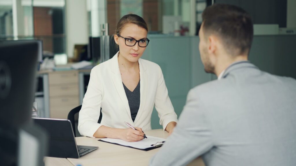 Two colleagues talking across a desk in an office during a workplace meeting