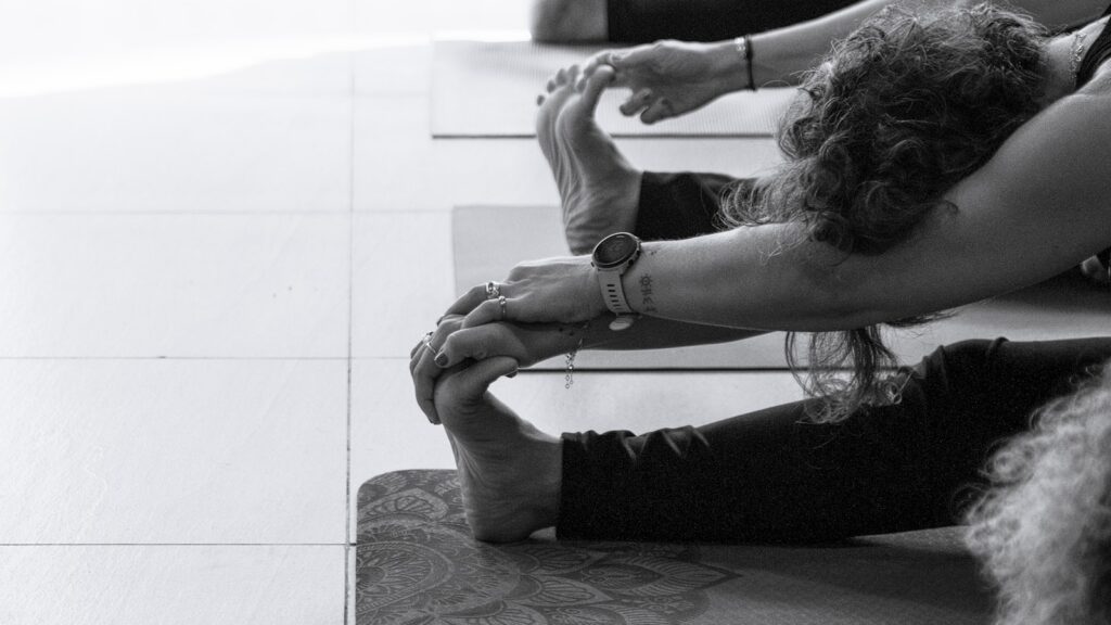 People stretching on yoga mats during a holistic wellness therapy session